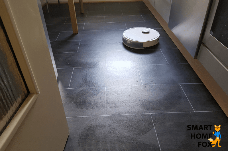 Ein Saugroboter mit Wischfunktion wischt den Boden in der Küche.